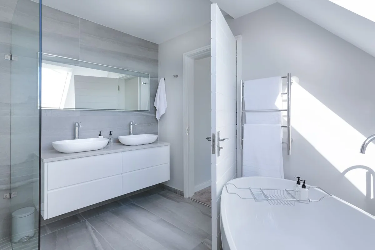 Salle de bain claire avec raclette à portée de main et fenêtre ventilation