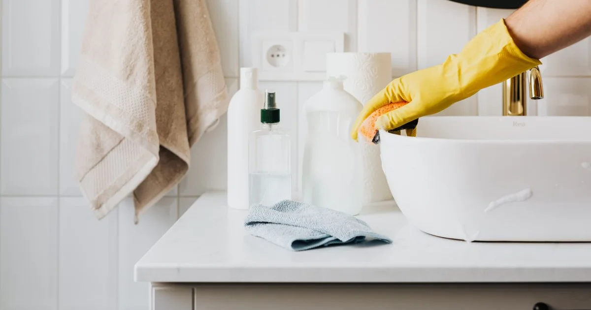 Baignoire acrylique blanche avec traces de calcaire sur les parois, vaporisateur et chiffon microfibre à côté