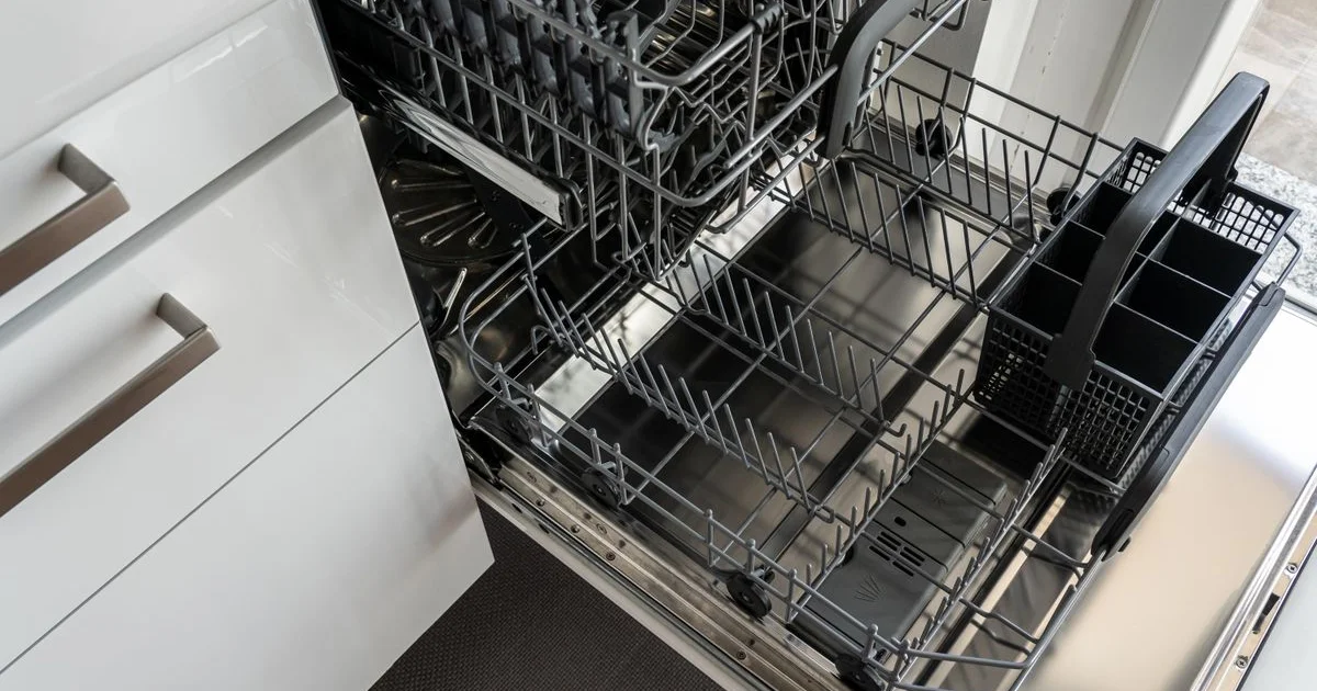 Lave-vaisselle ouvert montrant les paniers et l'intérieur inox et les bras gicleurs
