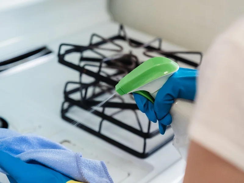 Personne avec gants utilisant spray et chiffon — entretien réfrigérateur