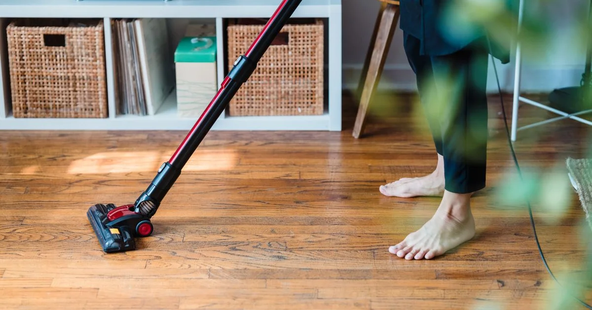 Balai microfibre plat sur un parquet en bois clair avec seau et flacon de savon noir liquide