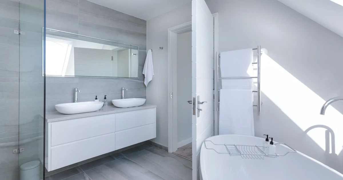 Flacon spray de savon noir dilué posé à côté d'une brosse WC en bambou devant une cuvette blanche propre, salle d'eau lumineuse