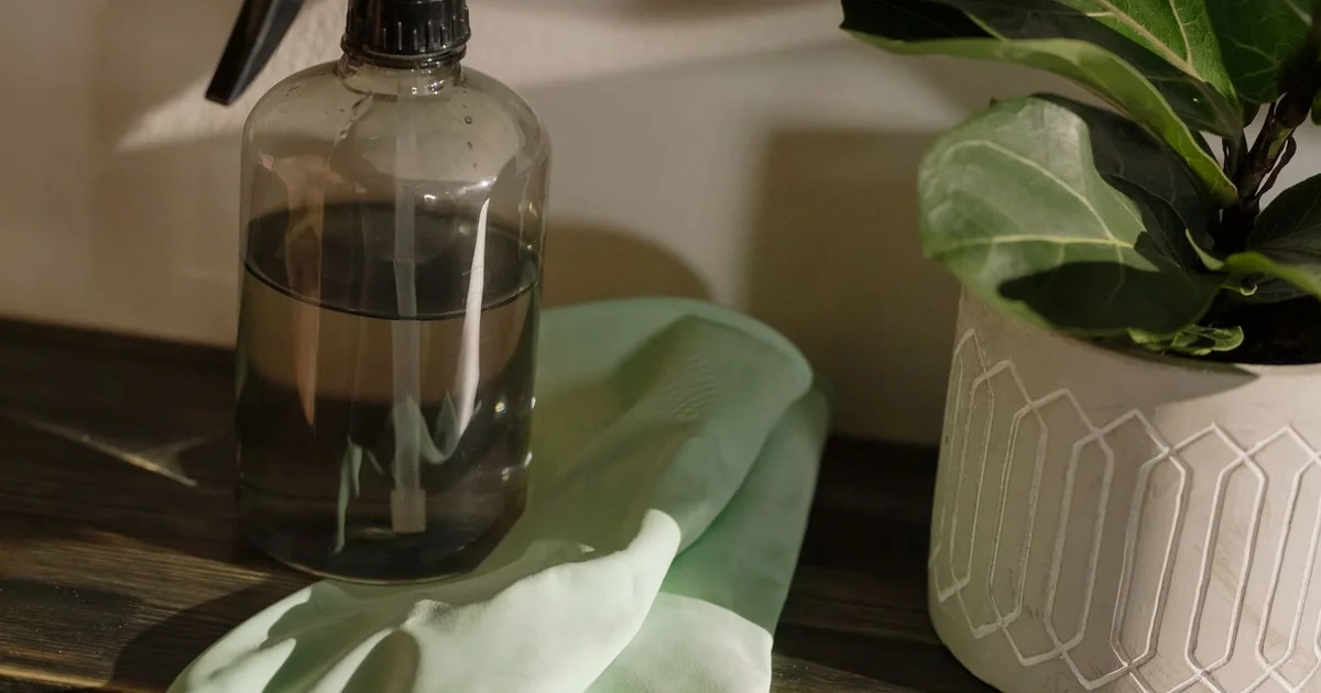 Flacon de vinaigre blanc ménager 5 litres avec spray et chiffons microfibres sur un plan de travail en bois